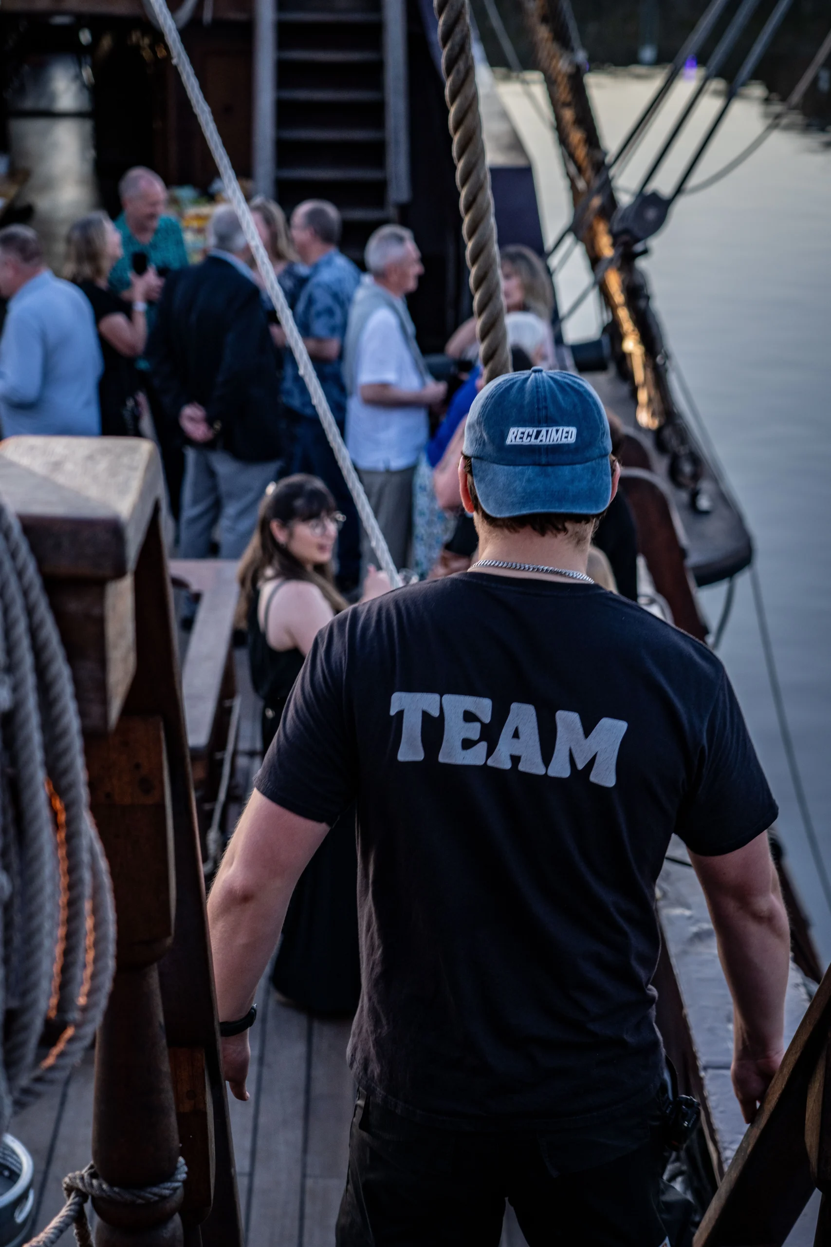 male with team written on the back of his shirt at a corporate boat event with people in the background
